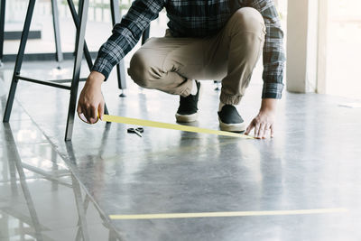 Rear view of man taking selfie on floor