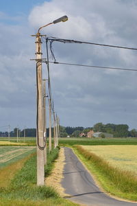 Street amidst field against sky