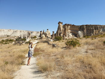 Rear view of woman walking on rocks against clear sky