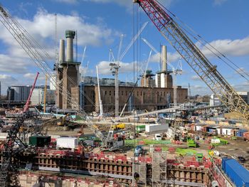 Cranes at construction site in city against sky