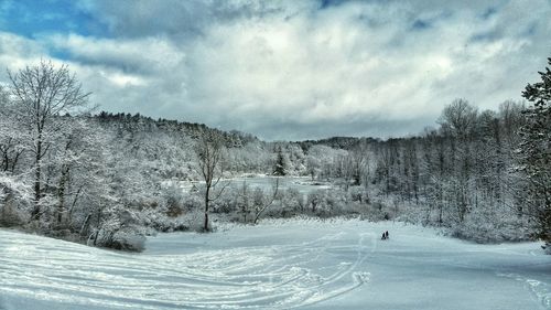 Snow covered landscape against cloudy sky