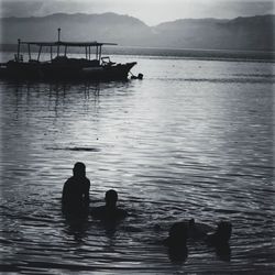 Silhouette people in sea against sky