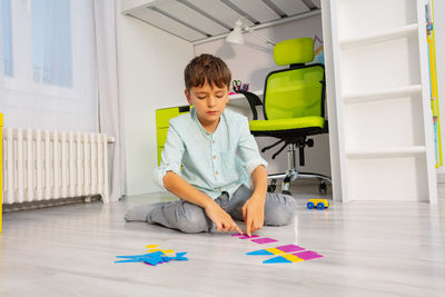 Portrait of young woman using mobile phone while sitting on floor at home