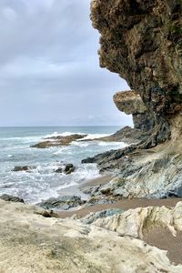 Rock formation on beach against sky