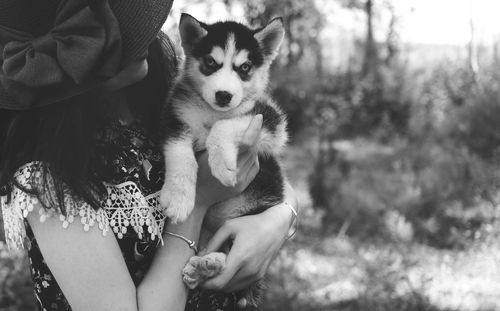 Woman holding dog against trees