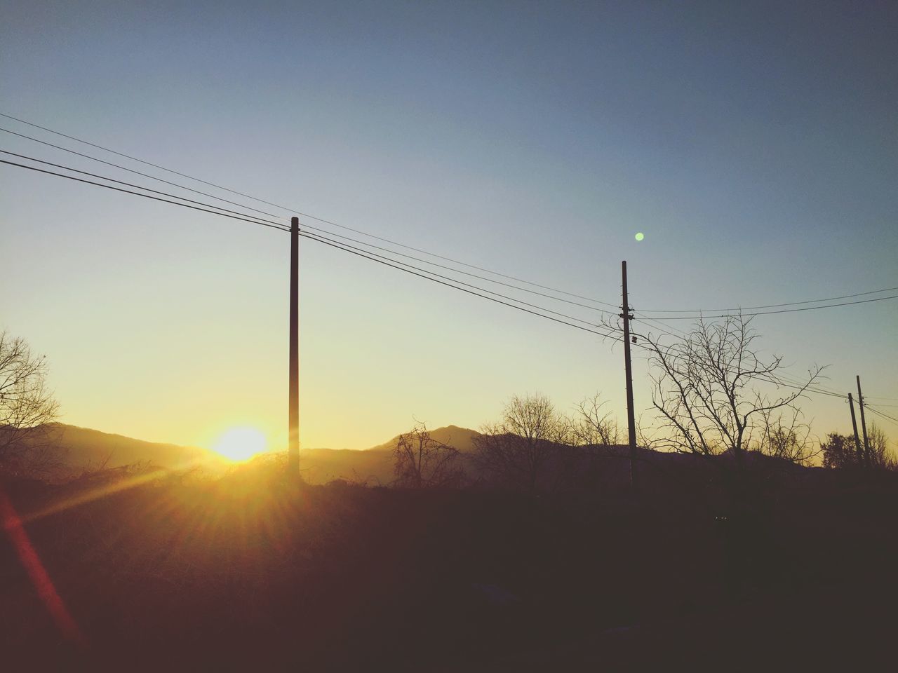 LOW ANGLE VIEW OF SILHOUETTE ELECTRICITY PYLONS AGAINST CLEAR SKY