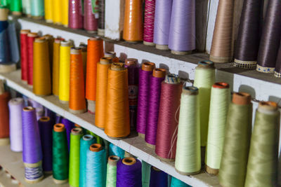 Close-up of multi colored spools on shelves at shop