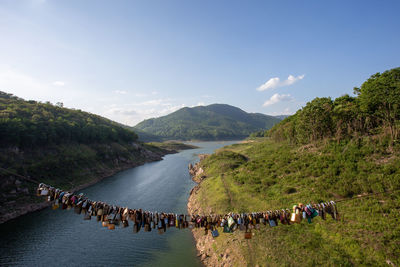 People on river by mountains against sky