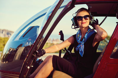 Female pilot wearing sunglasses sitting in helicopter