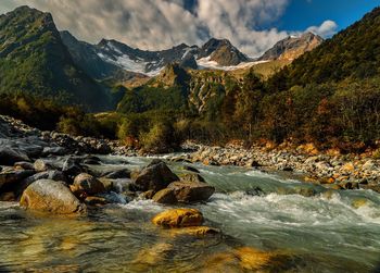 Stream flowing through rocks against sky