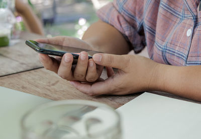 Midsection of man using mobile phone on table