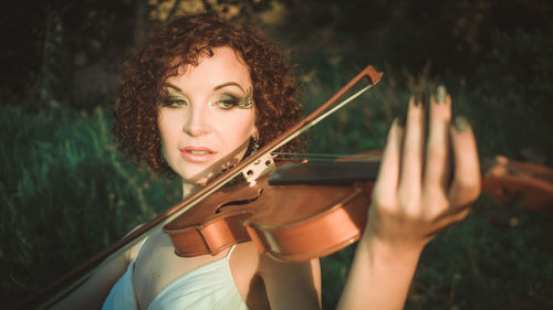 Close-up of woman playing violin while standing on field