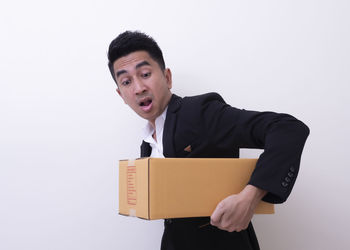 Young man holding camera against white background