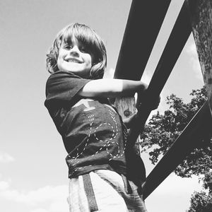 Low angle view of happy boy holding raining against sky