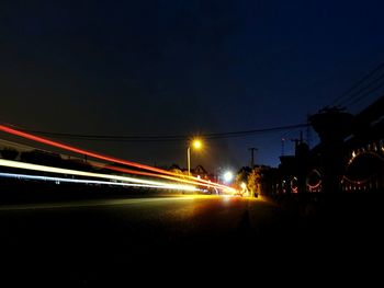 Light trails on road against sky at night