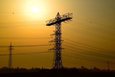 Low angle view of electricity pylon against sky during sunset