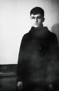 Portrait of young man standing against wall