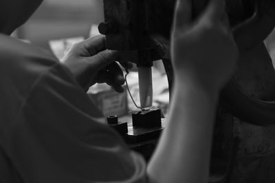 Midsection of woman using sewing machine in workshop