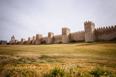 View of fort of the medieval wall un Ávila on field against sky