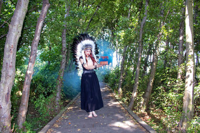 Full length of woman standing amidst trees in forest