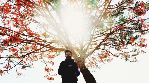 Man standing by tree against sky