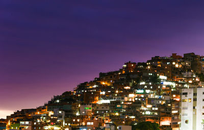 Illuminated cityscape against clear sky at night