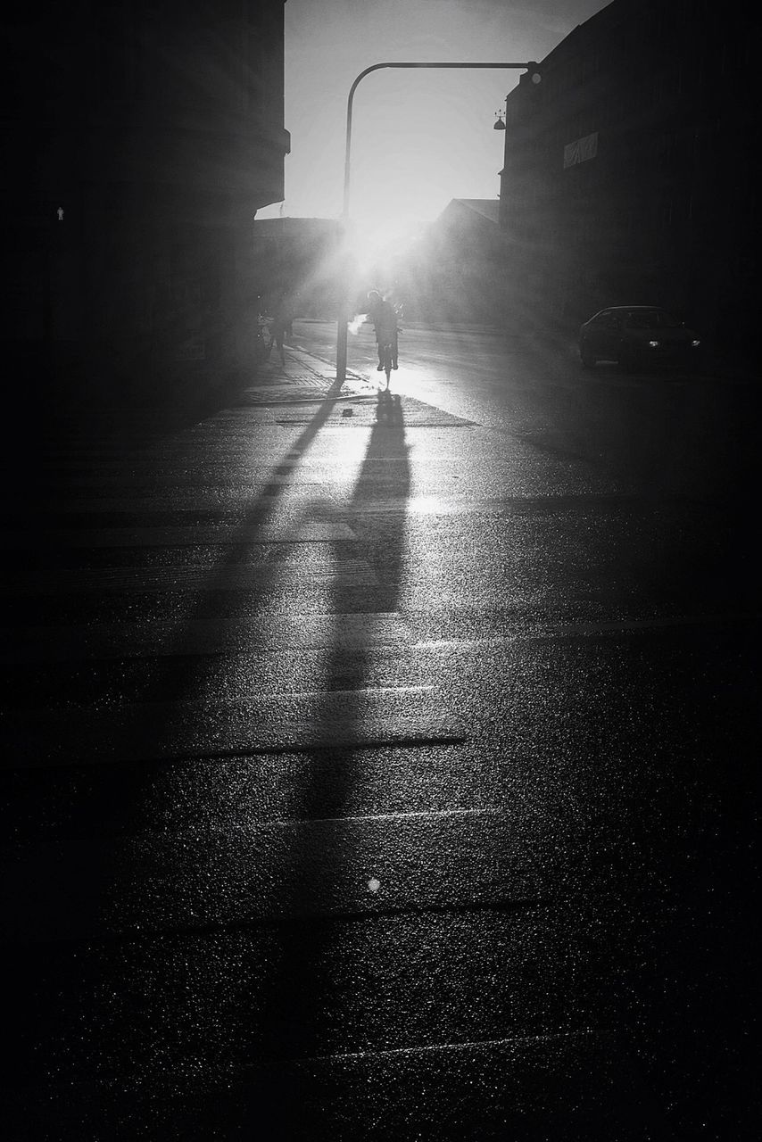 building exterior, architecture, built structure, walking, street, lifestyles, sunlight, full length, silhouette, leisure activity, men, shadow, unrecognizable person, road, the way forward, lens flare, sunbeam, person