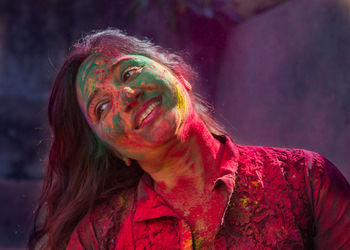 Smiling woman with colorful powdered paint on face during holi