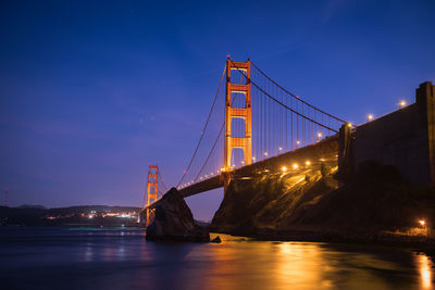 Low angle view of illuminated golden gate bridge over bay at night