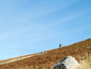 Low angle view of people on mountain against blue sky