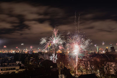 Firework display in city against sky at night