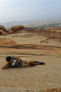 Man lying down on land against sky