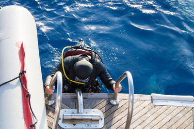 High angle view of scuba diver on boat ladder in sea