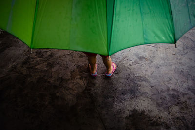 Low section of child with umbrella standing on road