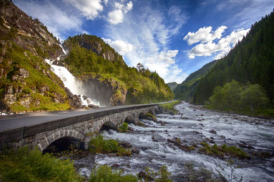 Scenic view of river by mountains against sky