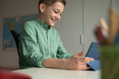 Side view of man using mobile phone while sitting on table