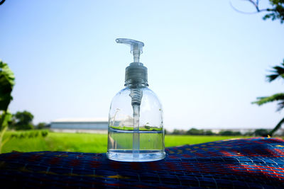 Close-up of glass bottle on table against clear sky