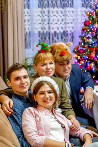 New year's portrait of a family of 4 people wearing carnival hats. adult children. christmas tree 