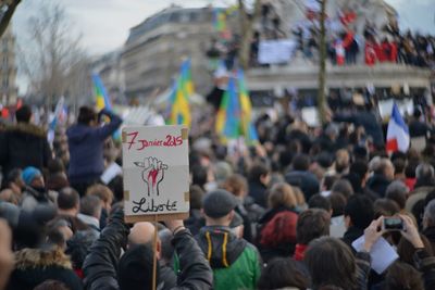 Crowd with text on paper protesting outdoors