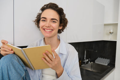 Portrait of young woman reading book at home