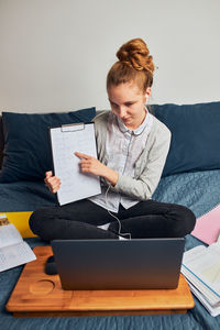 Smiling teenage girl showing homework during online lecture