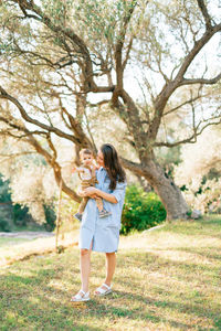 Full length of smiling young woman standing on tree