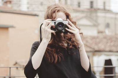 Portrait of young woman with red hair photographing