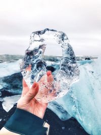 Close-up of person holding ice against sky