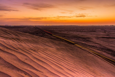 Scenic view of sand dunes against sky during sunset