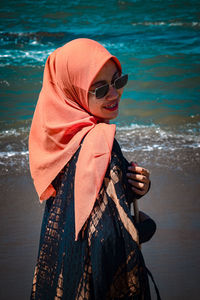 Portrait of woman wearing sunglasses standing on beach