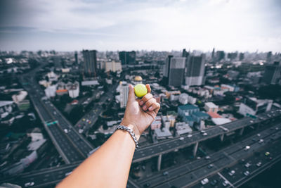 Cropped hand holding ball over cityscape