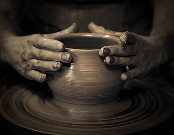 Midsection of woman making pottery at workshop