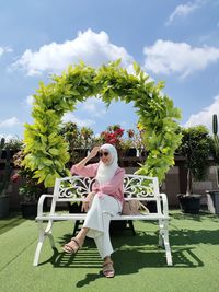 Full length of woman sitting in yard against sky