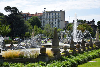 Fountain in park against buildings in city